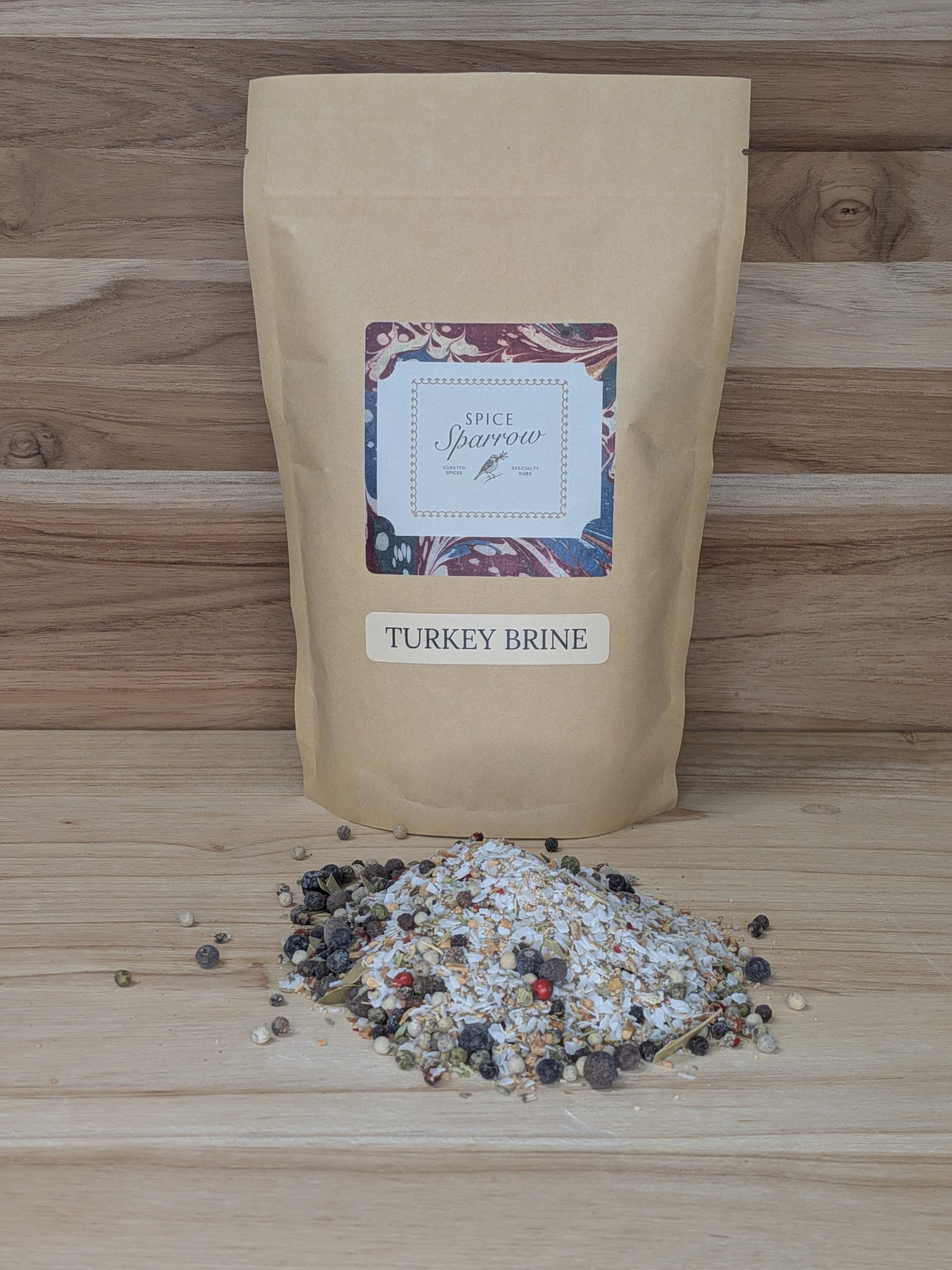1 lb. bag of Spice Sparrow Turkey Brine Seasoning packaged in a kraft paper stand up pouch with product poured on a wood surface